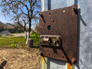 A rusty metal latch on the side of a metal door