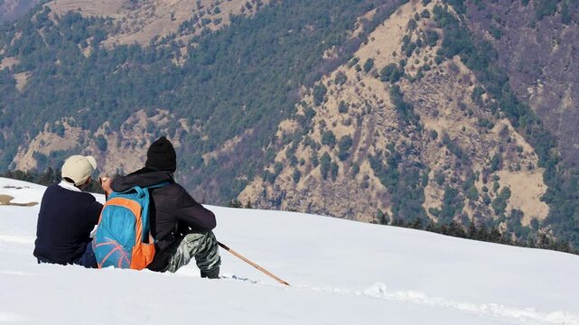 hikers relaxing at snowcap mountain trials with breathtaking view video is taken at Chopta Tungnath Himalayas mountain chandrashila trek uttarakhand india.