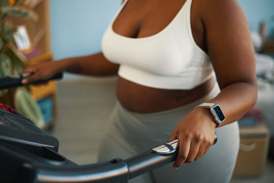 Person using treadmill wearing smartwatch and fitness gear in indoor setting emphasizing contemporary workout routine and healthy lifestyle
