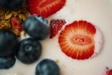 Close-up shot of fresh blueberries and sliced strawberries in yogurt with granola. Berries and granola creating a vibrant and healthy mixture