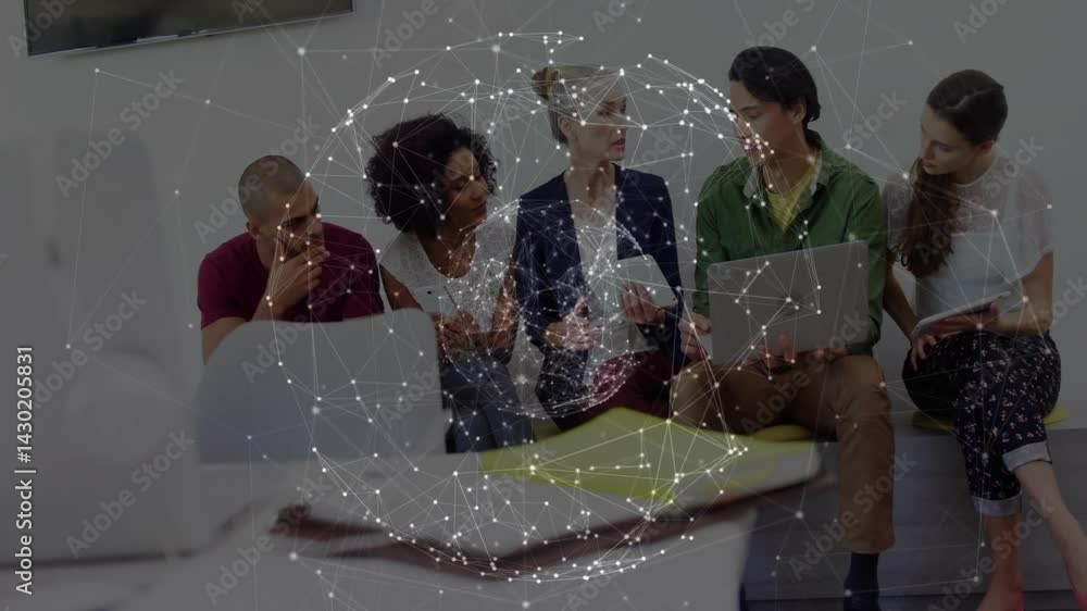 Poster tech team collaborating over devices in modern office with network overlay hovering above screens