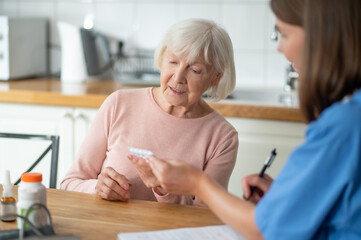 Medical professional giving assistance to elderly patient offering help with disease treatment