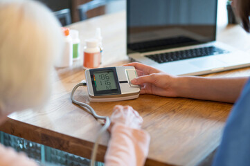 Female doctor helping senior patient with blood pressure test and pulse measurement