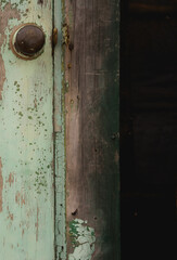 close up of rustic door knob on wooden door with paint peeling and rust showing grunge backdrop background of household metal door knob on old weathered wooden exterior door vertical image type space