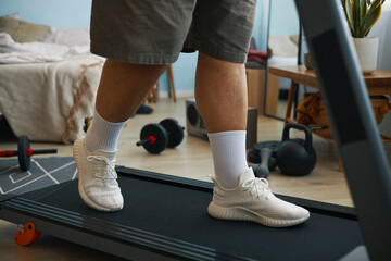 Image showing person's lower body while walking on treadmill in home gym. Various weights and...