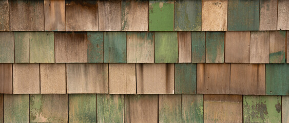horizontal color image of faded green blue painted wooden shingles or shakes on outside exterior wall of old building shakes and shingles in rows overlapping each other colorful background backdrop