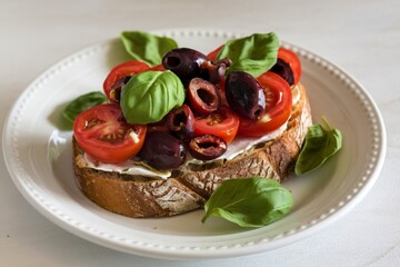 toasted slice of bread topped with sliced cherry tomatoes, olives