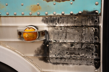 close up of rusty old transportation bus black marks on metal cage covered orange light turquoise rusted metal and bolts close cropped side of the bus just above wheel well horizontal grunge backdrop 
