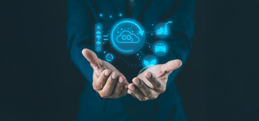 A person holds their hands out, displaying digital icons related to CO2 emissions, sustainability, and technology.