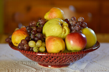 ceramic bowl with various ripe fruits at the table
