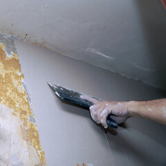 A man plastering a wall with a spatula. Apartment renovation