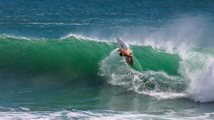 A fearless surfer carves through a powerful emerald wave at Snapper Rocks, Coolangatta, Queensland, surrounded by ocean spray and raw energy in this breathtaking moment of athleticism.
