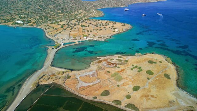 Reverse aerial of clear turquoise waters revealing the sunken city of Olous near Elounda, Crete.
