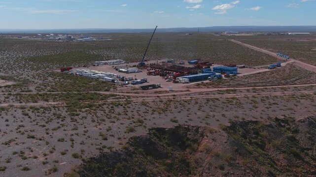 A drone flies over the Vaca Muerta fracking field in Neuqu&eacute;n. Red and blue trucks, as well as white trailers, can be seen. A long line of sand trucks await their turn to unload.