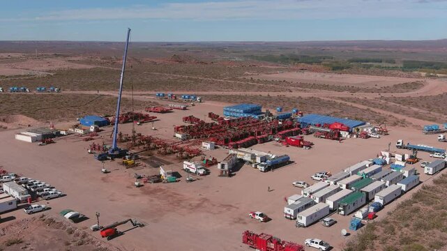 Drone flies in a 360-degree lateral view over the fracking field in Vaca Muerta, Neuqu&eacute;n. Red and blue trucks, as well as white trailers, can be seen.