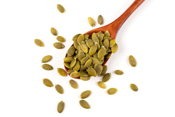 Pumpkin seeds lie in a brown wooden spoon in close-up on a white isolated background.