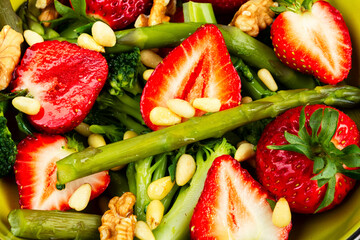 Green mixed salad with green asparagus and strawberries.