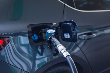 Fueling a dark sedan at a modern gas station during daylight hours