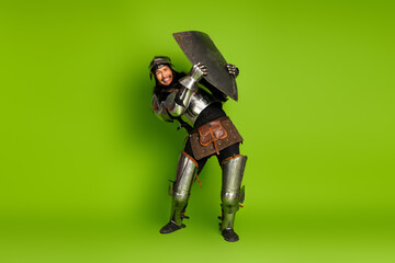 Young man in medieval armor posing playfully against a vibrant green background