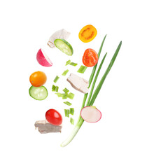 Pieces of chicken meat and fresh vegetables falling on white background