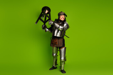 Young man in medieval knight armor posing against a vibrant green background