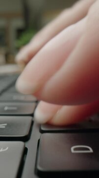 Close-up of womans fingers typing on laptop keyboard in modern caf&eacute;