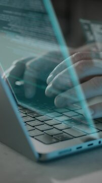 Vertical video of hands typing on laptop keyboard with graphics