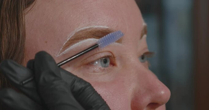 Close-up of a woman's face. The procedure for coloring and shaping eyebrows