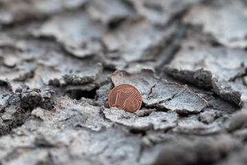 1 euro cent coin in cracked dry ground. One euro cent coin placed in cracked, arid soil — a concept image representing minimal value, poverty, financial problems in Europe