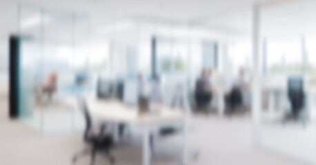 Blurred office interior with desks chairs and people working in the background. Elegant business background for banner display background, magazine poster and web display.