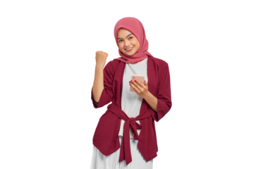 Excited young Asian Muslim woman in hijab celebrating with smartphone while raising fist in joy isolated on transparent background