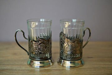 Two traditional Russian tea glass holders on a wooden table on a grey background 