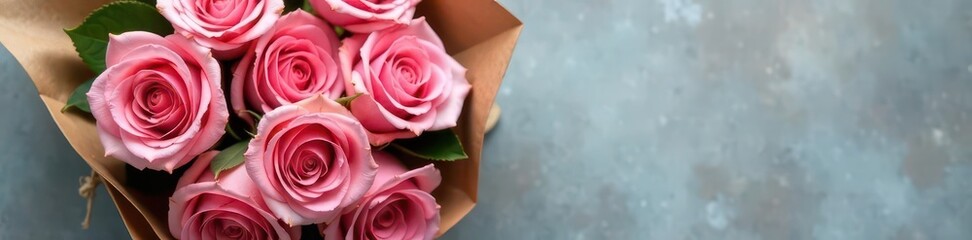 Fototapeta premium A dozen blushing pink roses tied with twine, nestled in brown kraft paper on a grey surface, celebration, brown