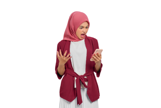 Angry young Asian Muslim woman in hijab expressing frustration while using smartphone isolated on transparent background