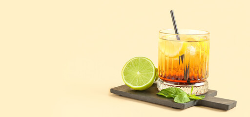 Cutting board with glass of delicious Long Island iced tea, lime and mint leaves on color background