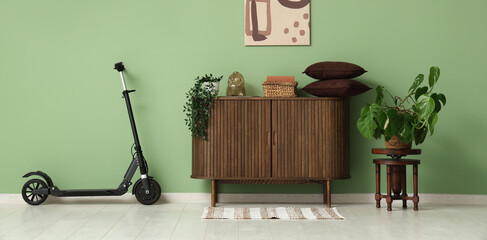 Interior of living room with electric scooter, commode and painting