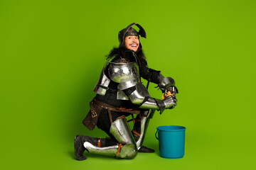 Knight in full armor with modern expression on green background holding an object next to a blue...