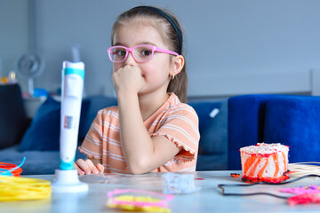 Little girl in pink glasses sits at table