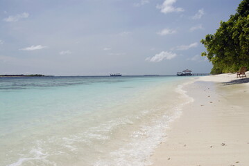 Tranquil tropical beach with clear blue water and white sand in the Maldives 