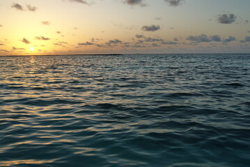 Tranquil ocean sunset with rippling waves and scenic cloudscape