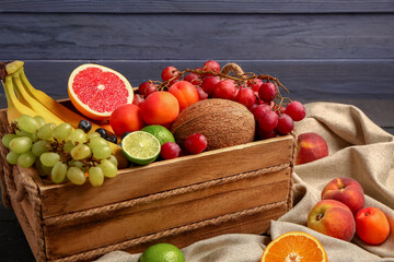 Box with different fresh fruits on blue wooden background