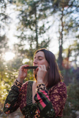 young girl plays the harmonica in the forest. the girl loves to play the harmonica.