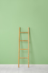 Wooden ladder near green wall in room