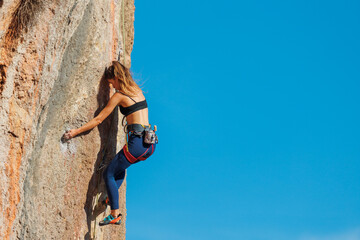 The girl climbs the rock. The climber is training to climb the rock. A strong athlete overcomes a...