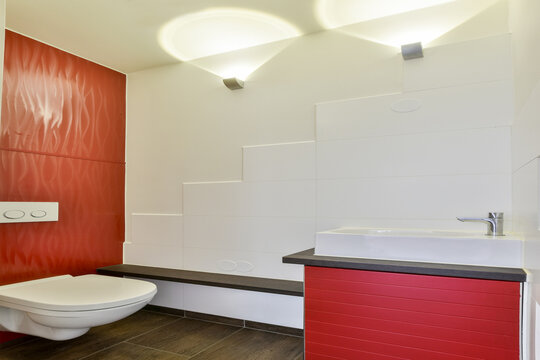 A contemporary bathroom showcasing sleek lines, a stylish red accent wall, and minimalist fixtures that create a clean and modern aesthetic.