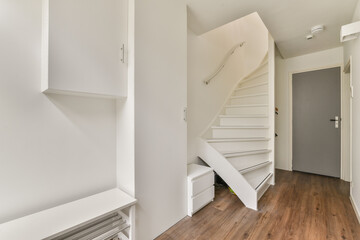 A sleek and bright hallway featuring modern architecture, clean lines, and minimalist decor. The well-lit space has a stylish staircase and functional storage units.