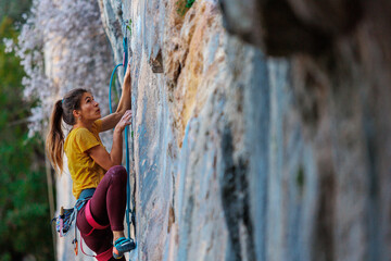 A woman climbs a rock, a strong girl trains strength and endurance, extreme sport, rock climbing..