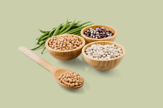 Chickpeas, beans, and green beans displayed in wooden bowls and spoon, promoting healthy eating
