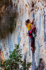 A woman climbs a rock, a strong girl trains strength and endurance, extreme sport, rock climbing..