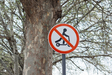 Sign in park with crossed out electric scooter. Ban on riding scooter in public place on street of...
